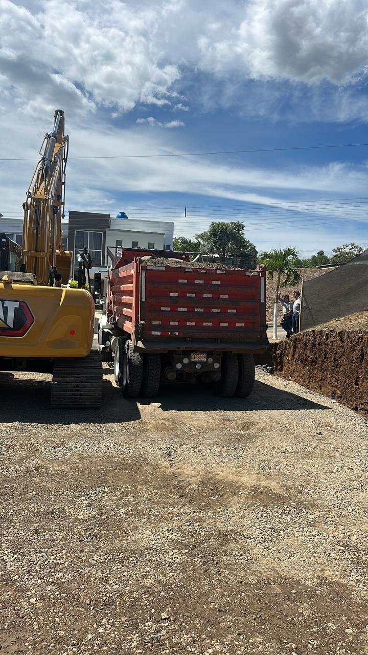 Camión de volteo cargado con material y excavadora en sitio